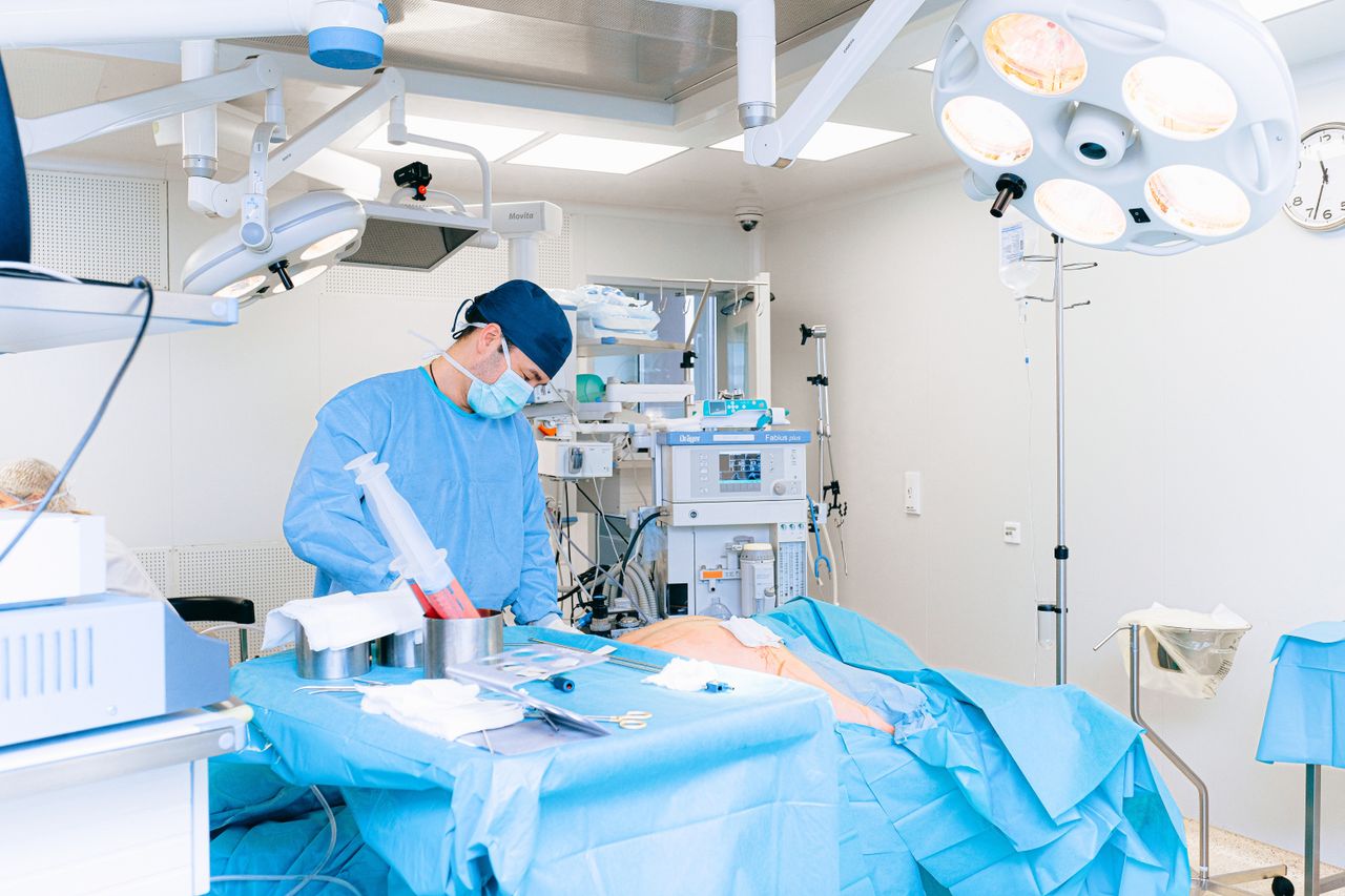 About Experienced surgeon performing a procedure in a well-equipped operating room.
